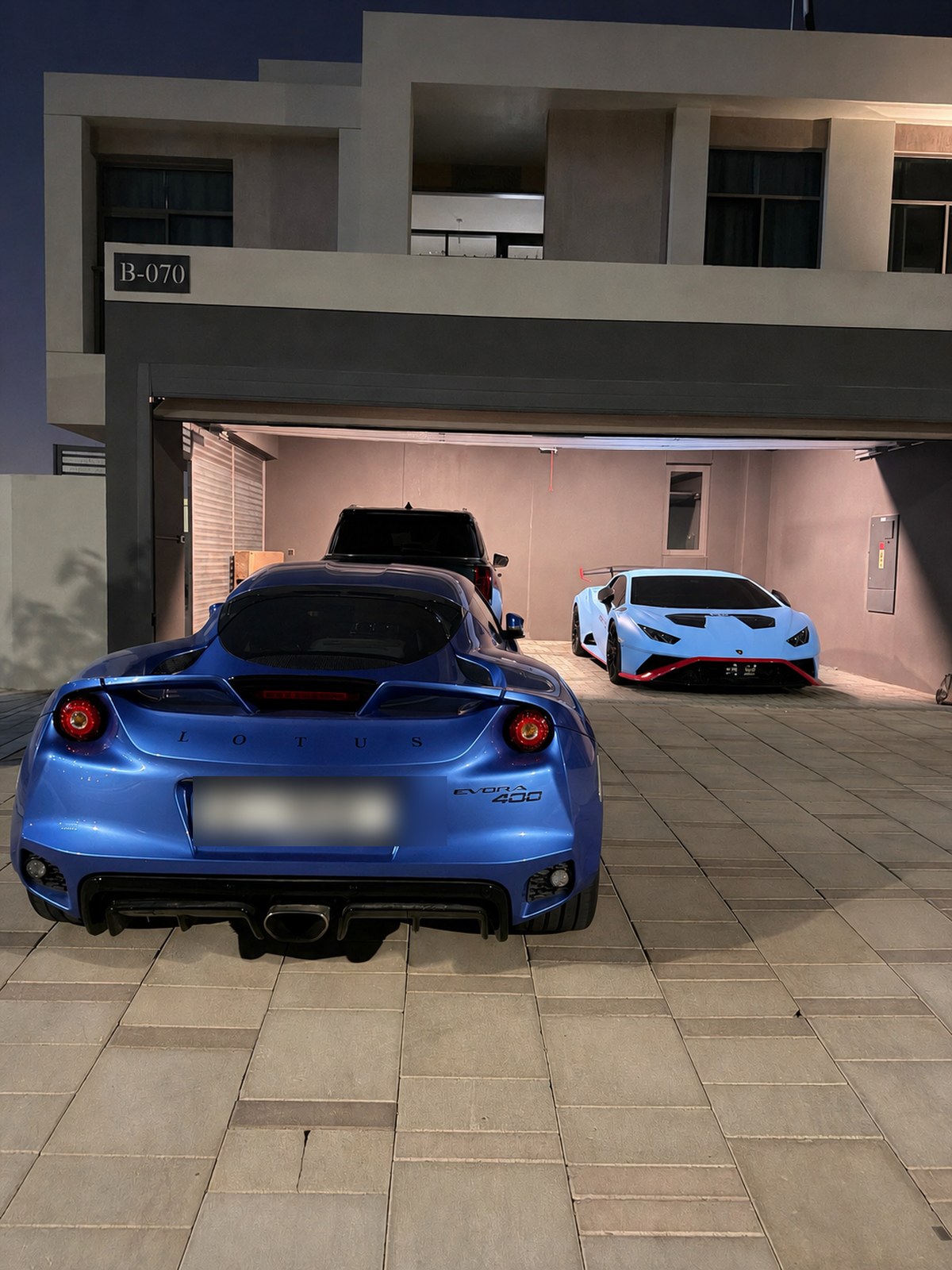 Ceramic-coated blue Lotus Evora with Lamborghini Huracan in garage